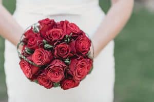 Eine Braut hält einen Strauß roter Rosen.