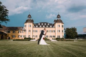 Ein Brautpaar steht vor einem großen Schloss.