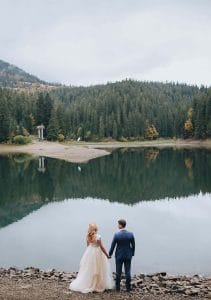 Eine Braut und ein Bräutigam stehen neben einem See.