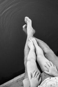 Ein Schwarz-Weiß-Foto der Füße eines Paares auf einem Dock.