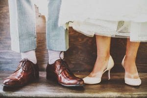 Eine Braut und ein Bräutigam stehen nebeneinander und tragen hochhackige Schuhe.