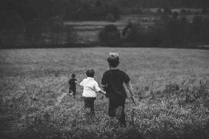 Zwei Jungen laufen in Schwarz und Weiß durch ein Feld.