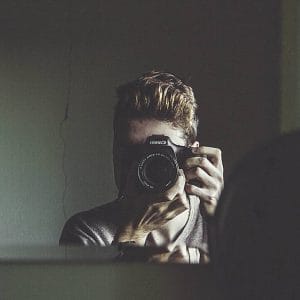 Ein Mann macht ein Foto mit einer Kamera im Spiegel.
