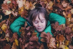 Ein kleiner Junge, der in einem Stapel Blätter liegt.