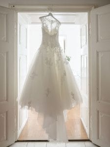 Ein Hochzeitskleid, das in einer Tür hängt.