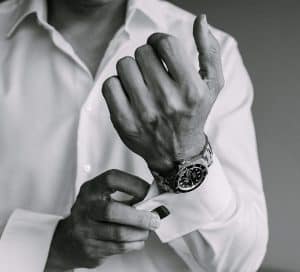 Schwarz-Weiß-Foto eines Mannes, der seine Uhr justiert.