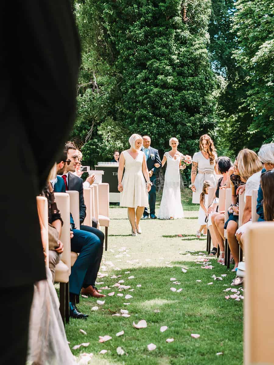 Eine Braut und ein Bräutigam gehen bei einer Hochzeit den Gang entlang.