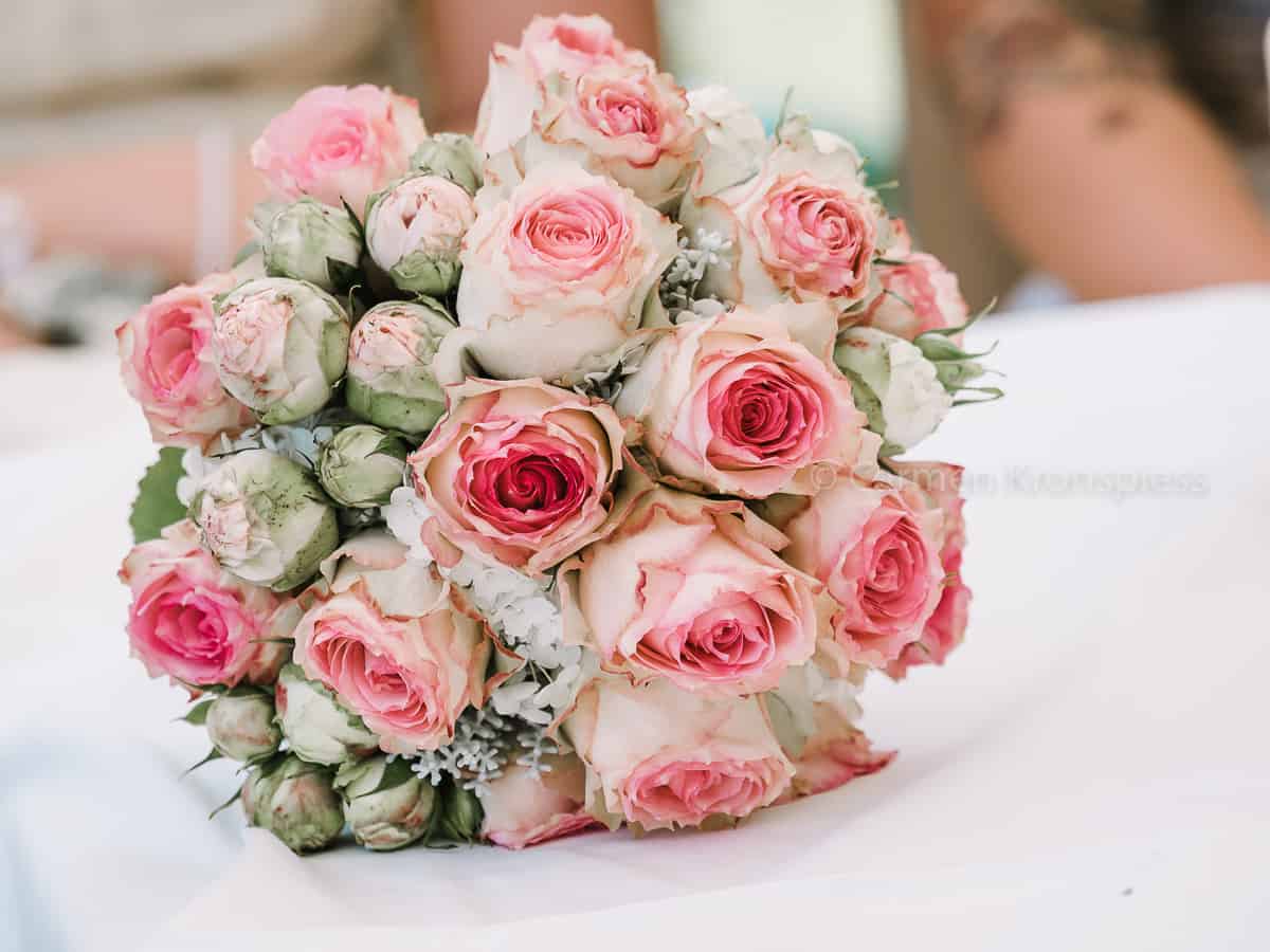 Auf einem Tisch steht ein Strauß rosa Rosen.