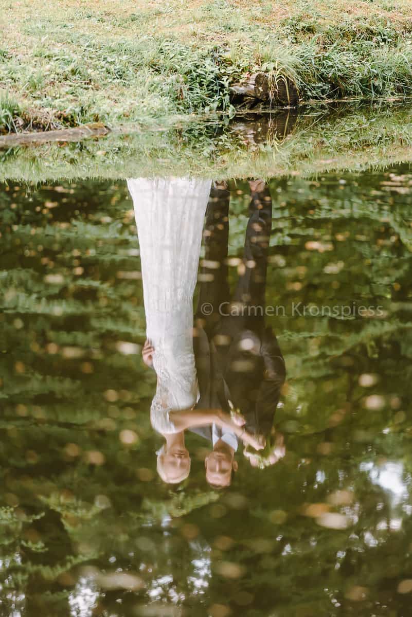 Eine Braut und ein Bräutigam stehen in einem Teich.
