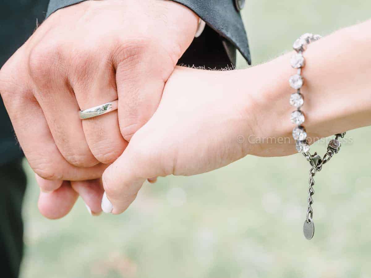 Ein Mann und eine Frau halten sich an den Händen und tragen Eheringe.