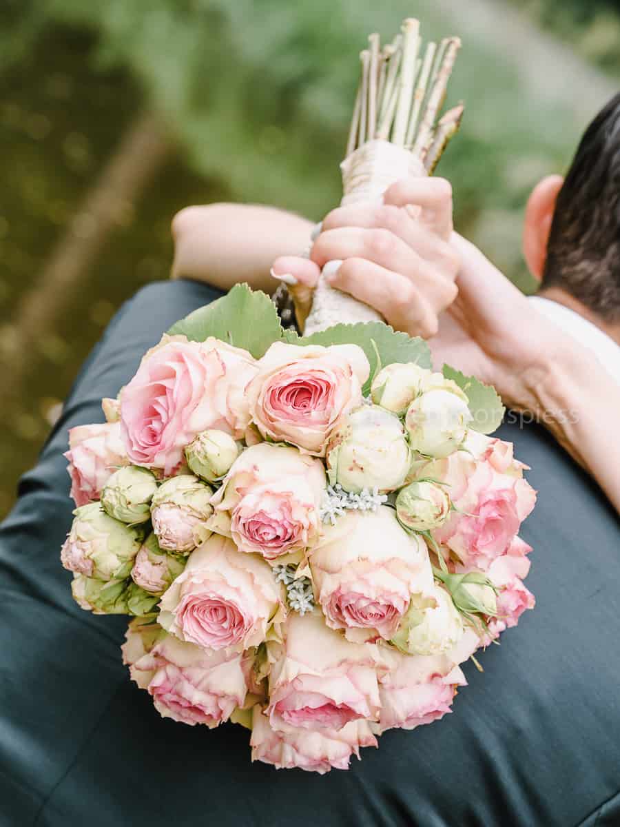Eine Braut und ein Bräutigam halten einen Strauß rosa Rosen.