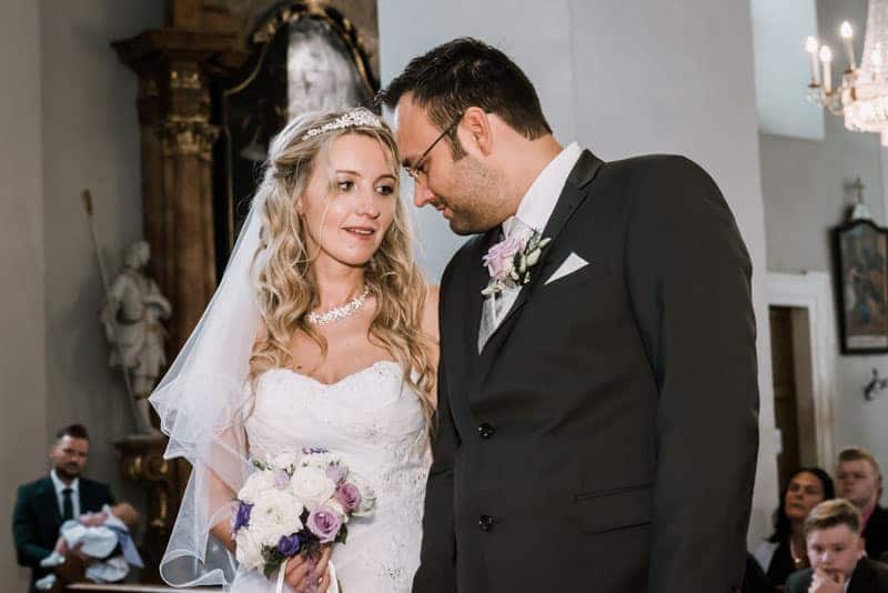 Eine Braut und ein Bräutigam schauen sich in einer Kirche an.