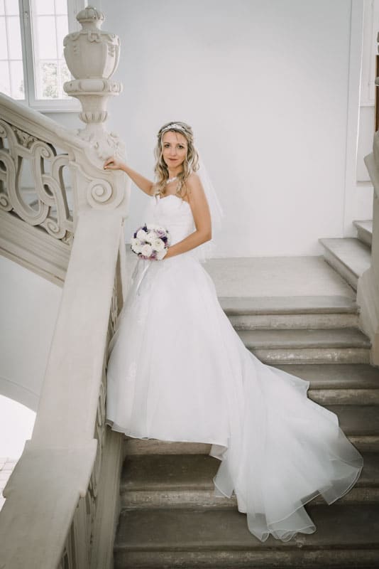 Eine Braut in einem weißen Kleid steht auf einer Treppe.