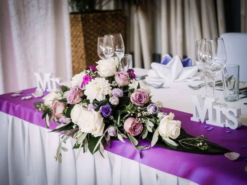 Ein lila-weißer Tisch mit Blumen und einem „Herr-und-Frau“-Schild.