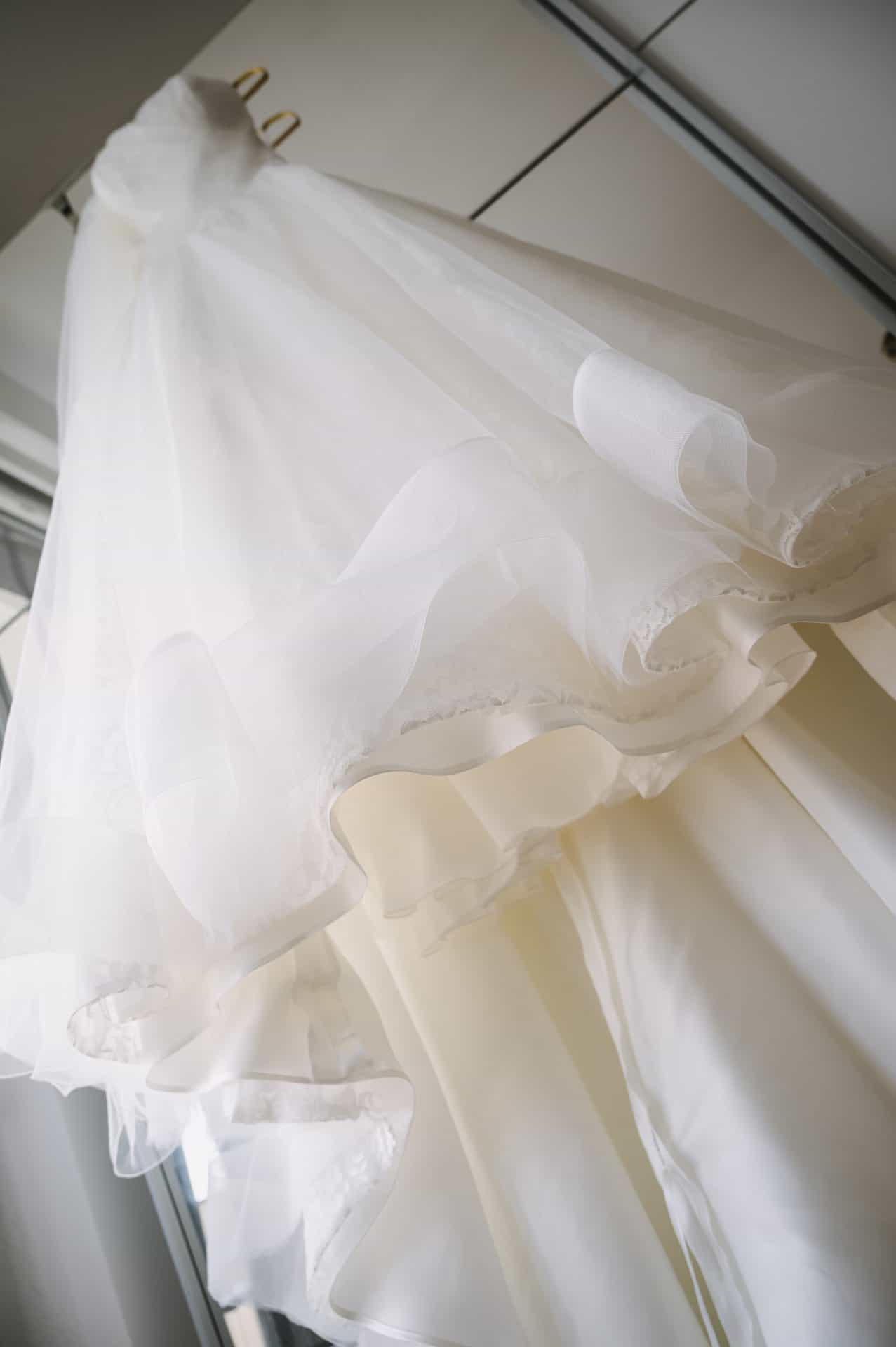Ein weißes Hochzeitskleid, das an einem Spiegel hängt.