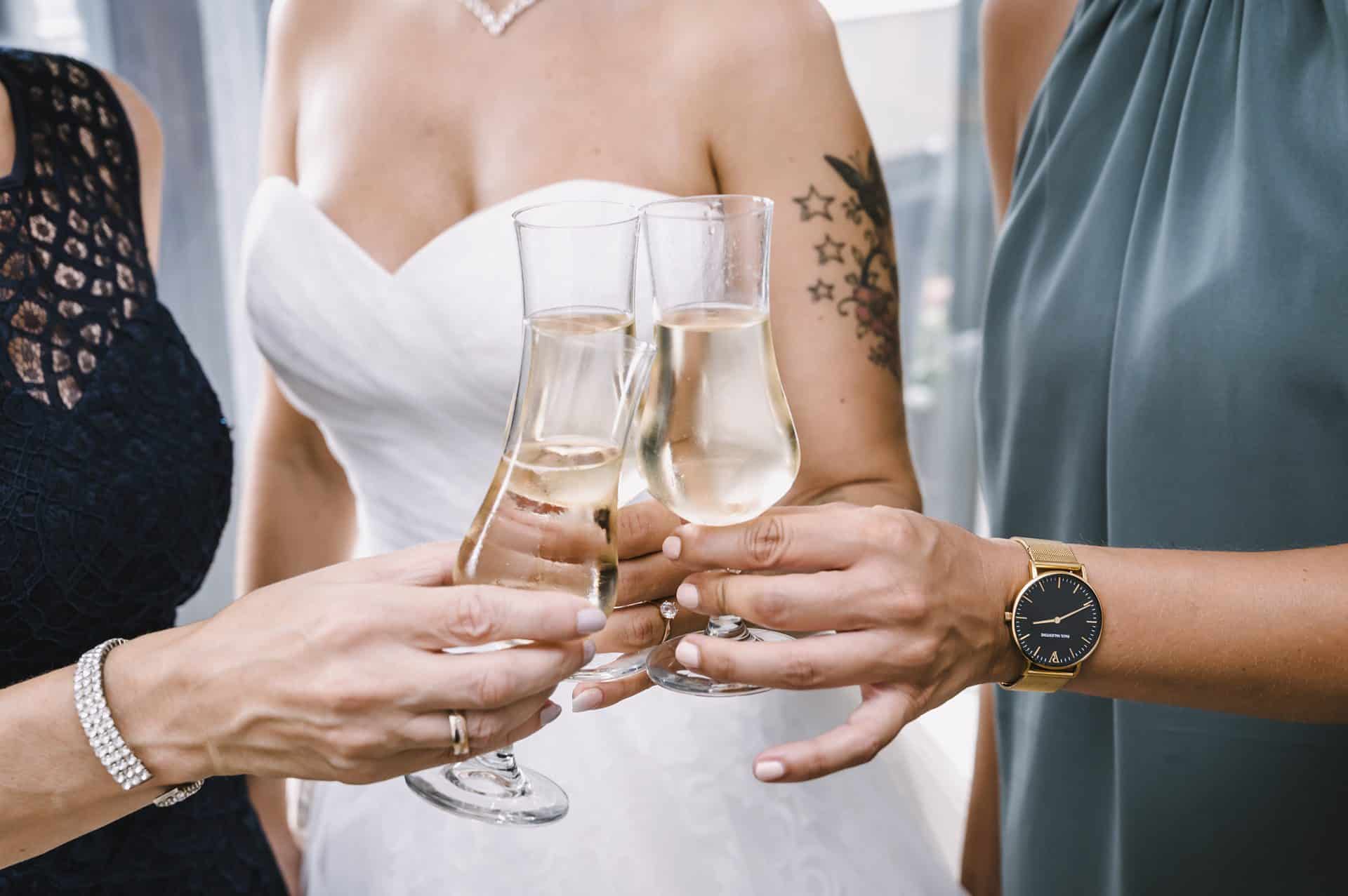 Drei Brautjungfern stoßen mit Champagnergläsern an.