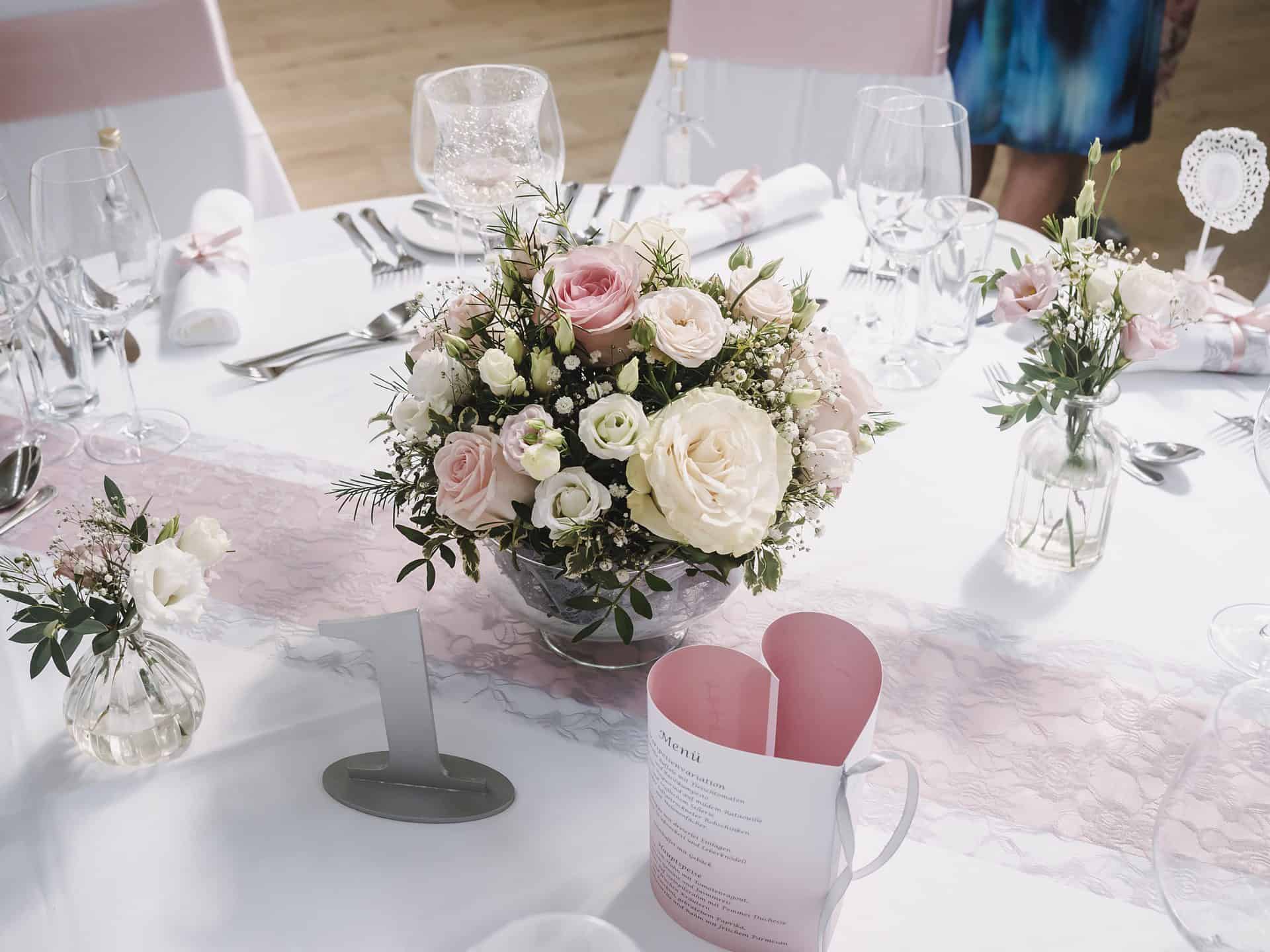 Eine Tischdekoration mit rosa und weißen Blumen.