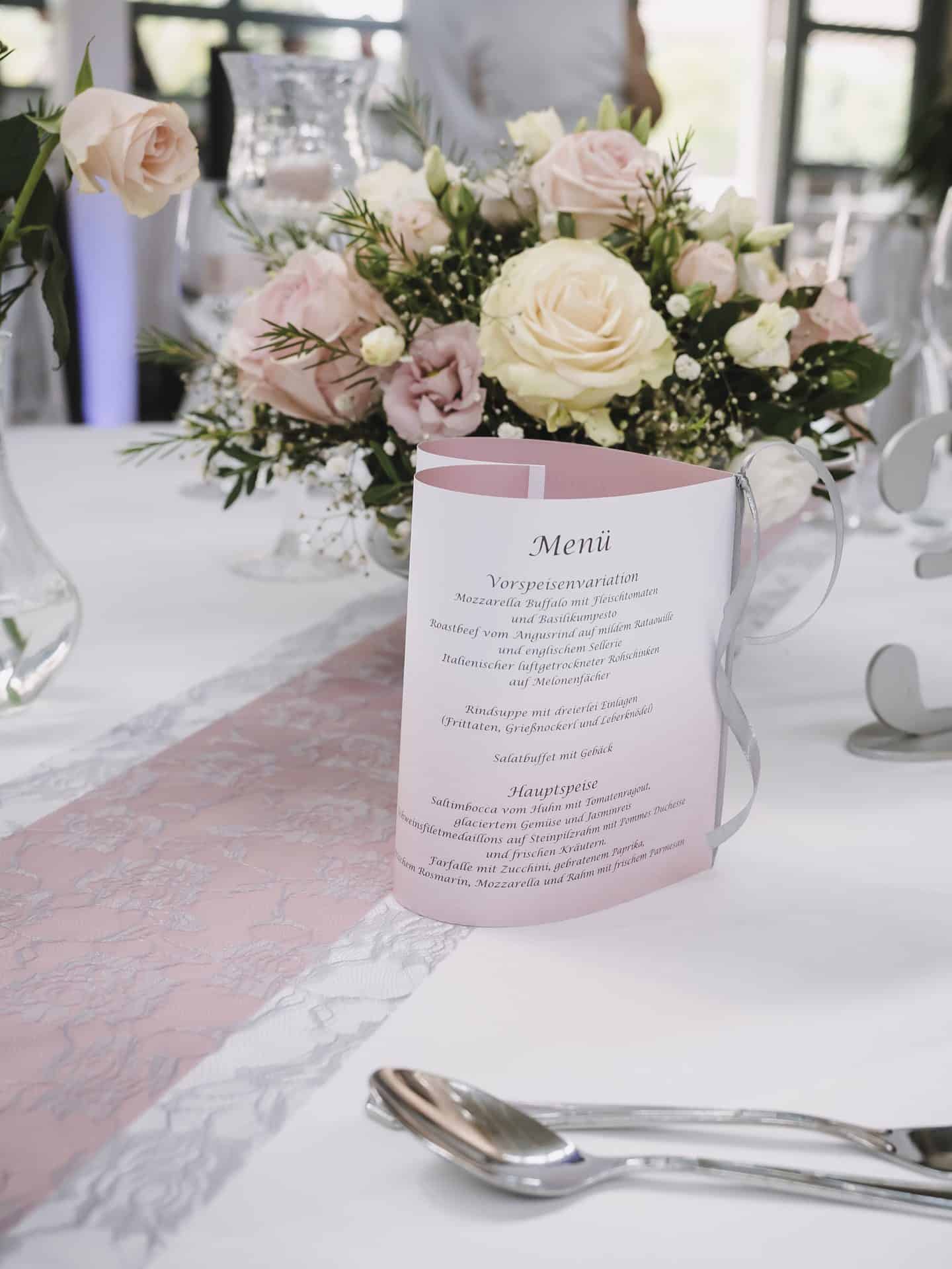 Ein gedeckter Tisch mit rosa Blumen und Besteck.