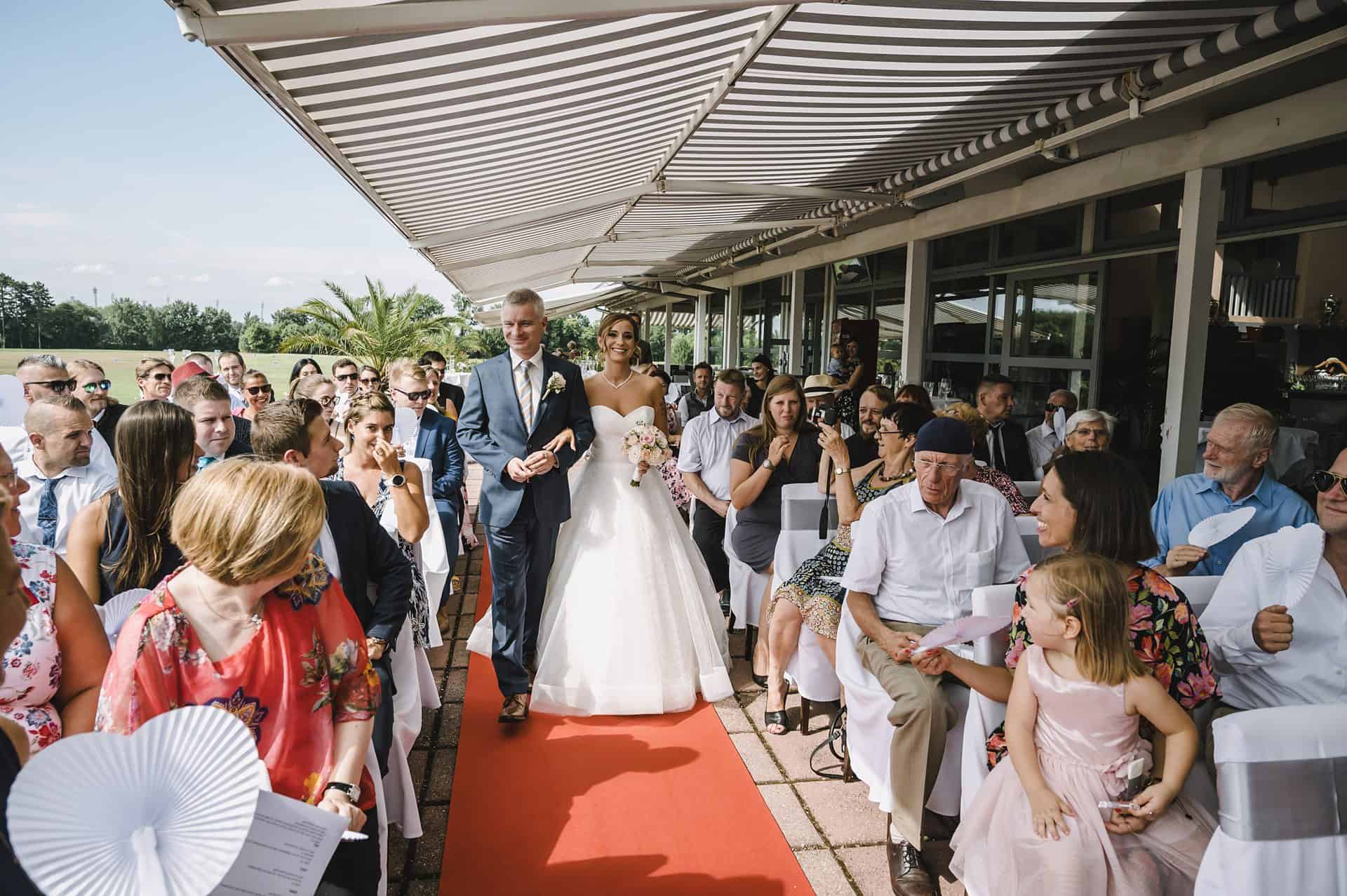 Eine Braut und ein Bräutigam gehen bei einer Hochzeitszeremonie den Gang entlang.