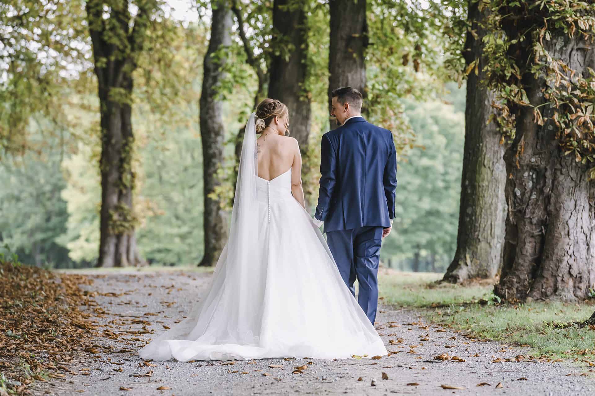 Eine Braut und ein Bräutigam gehen einen Pfad im Wald entlang.