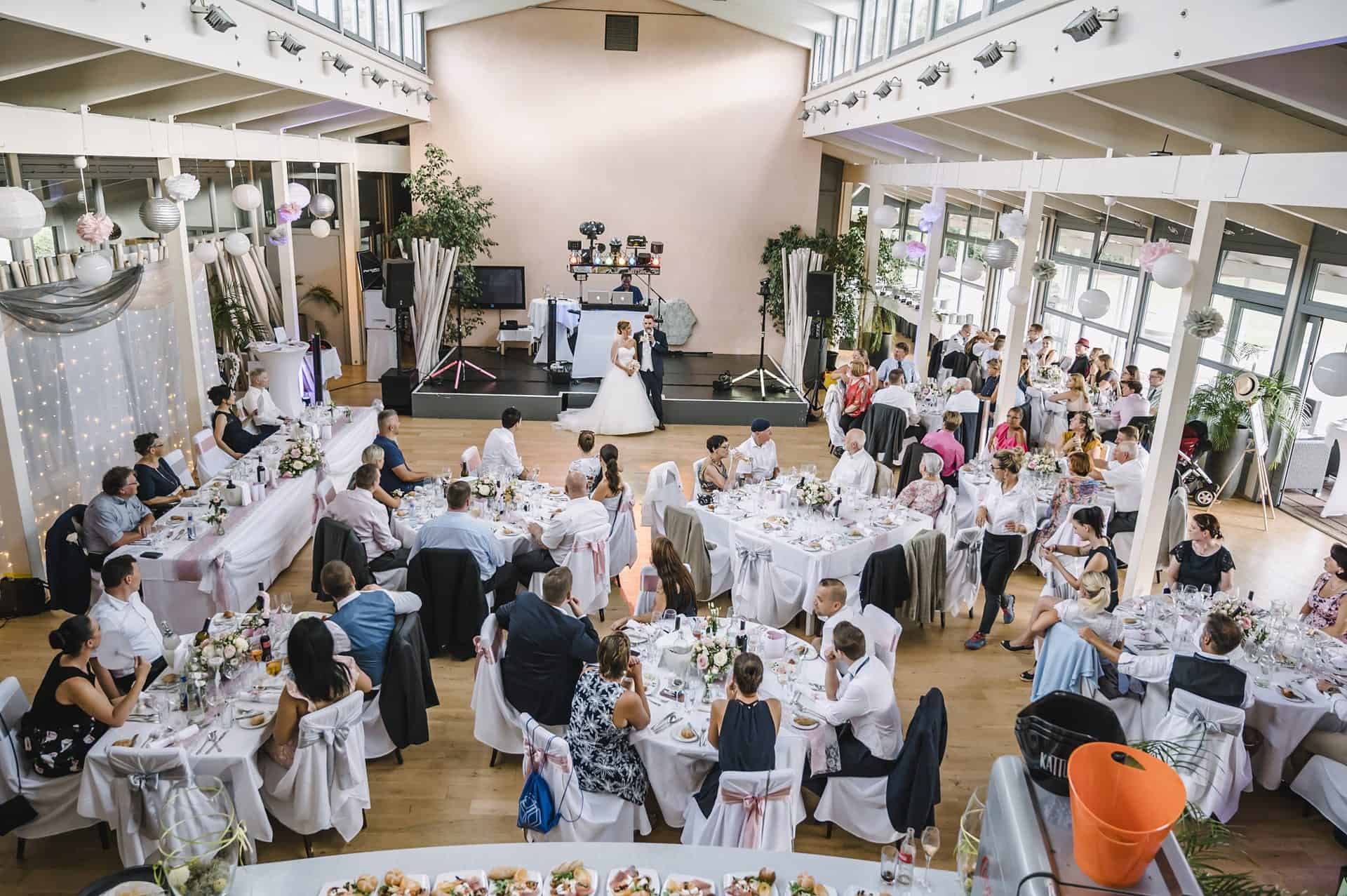 Eine Hochzeitsfeier in einem großen Raum mit Tischen und Stühlen.