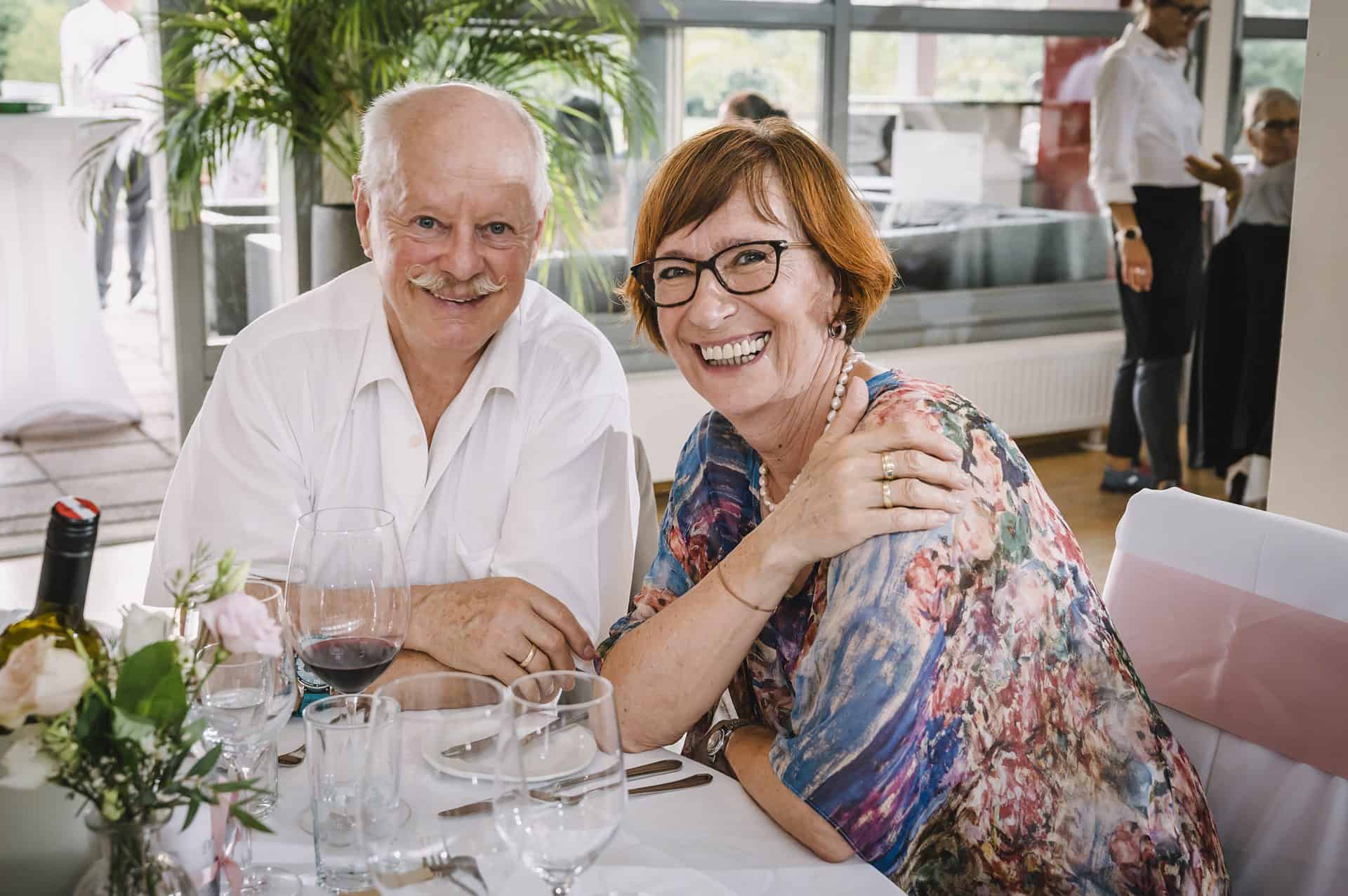 Ein älteres Paar lächelt an einem Tisch in einem Restaurant.