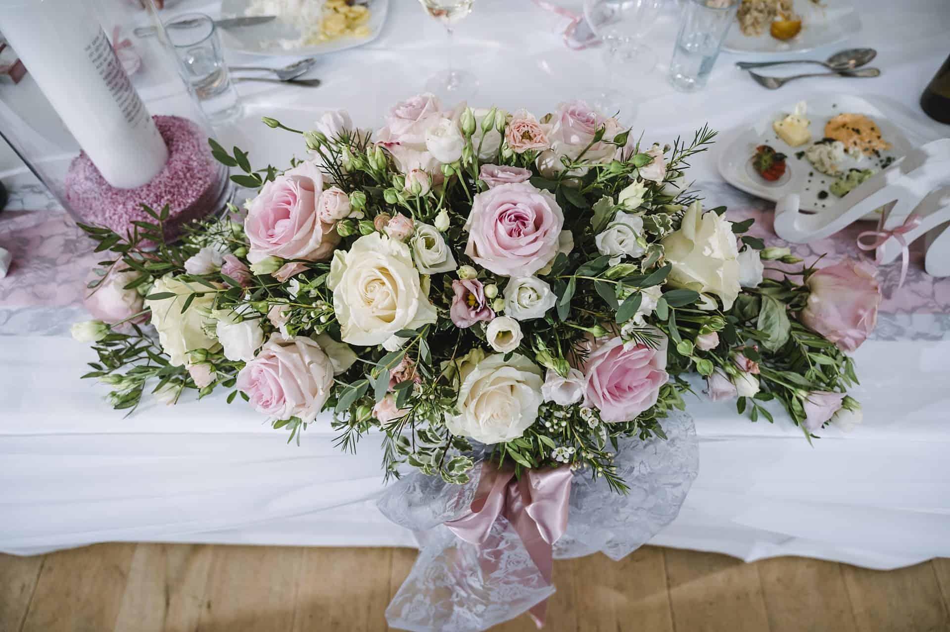 Ein mit rosa und weißen Rosen geschmückter Hochzeitstisch.