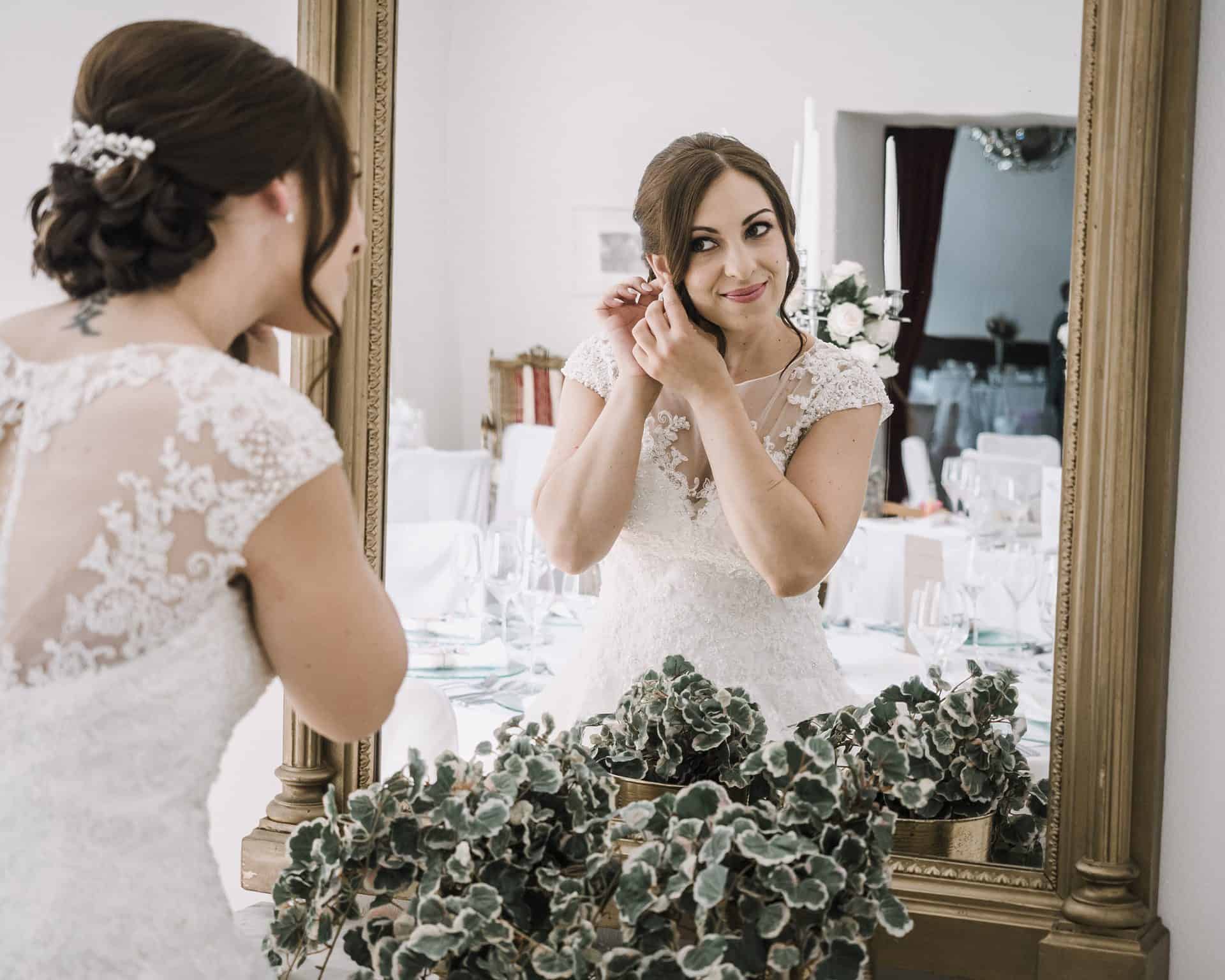 Eine Braut setzt ihren Ehering vor einem Spiegel an.