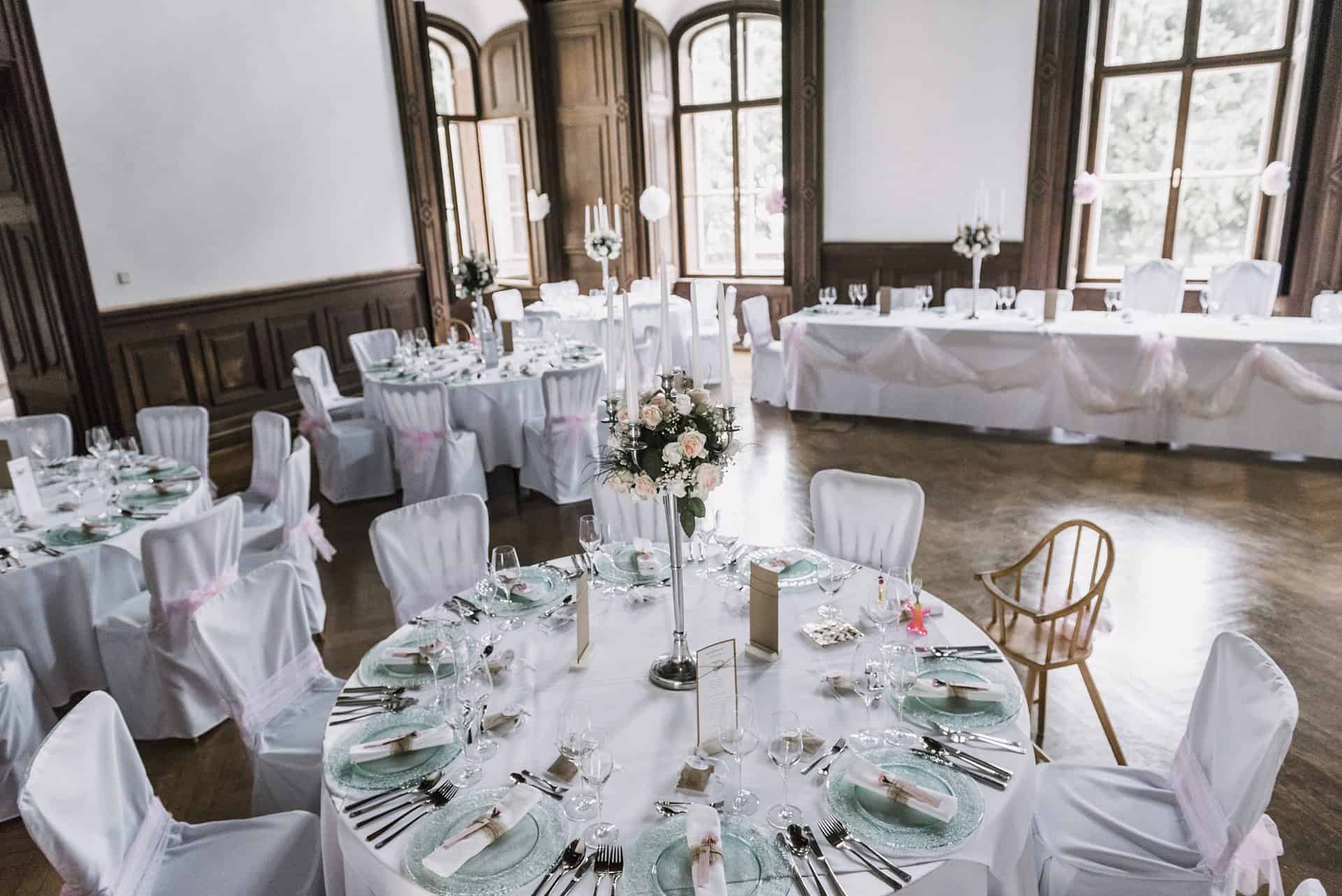 Eine Hochzeitsfeier in einem großen Raum mit weißen Tischen und Stühlen.