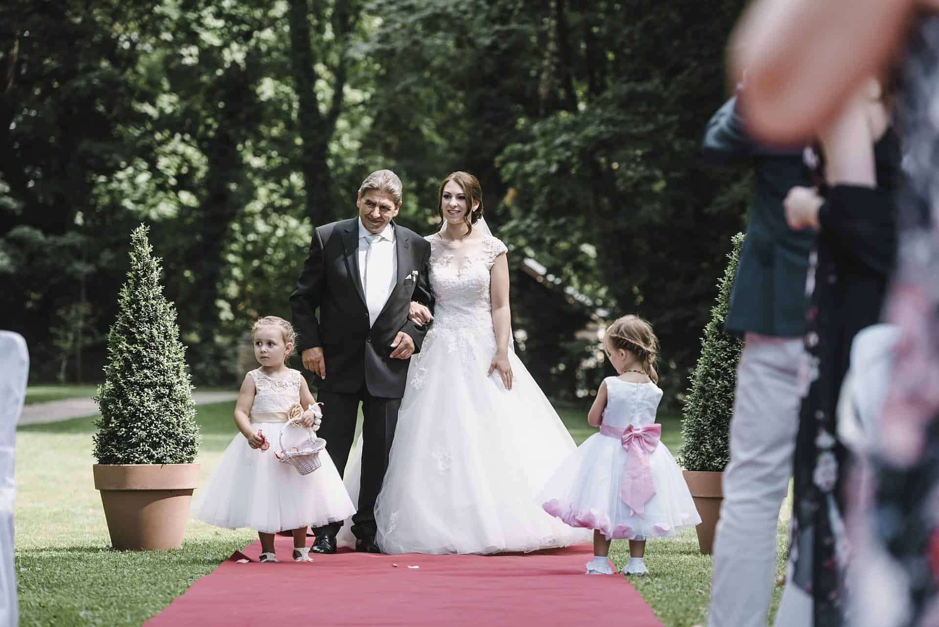 Eine Braut und ein Bräutigam laufen bei einer Hochzeit über einen roten Teppich.