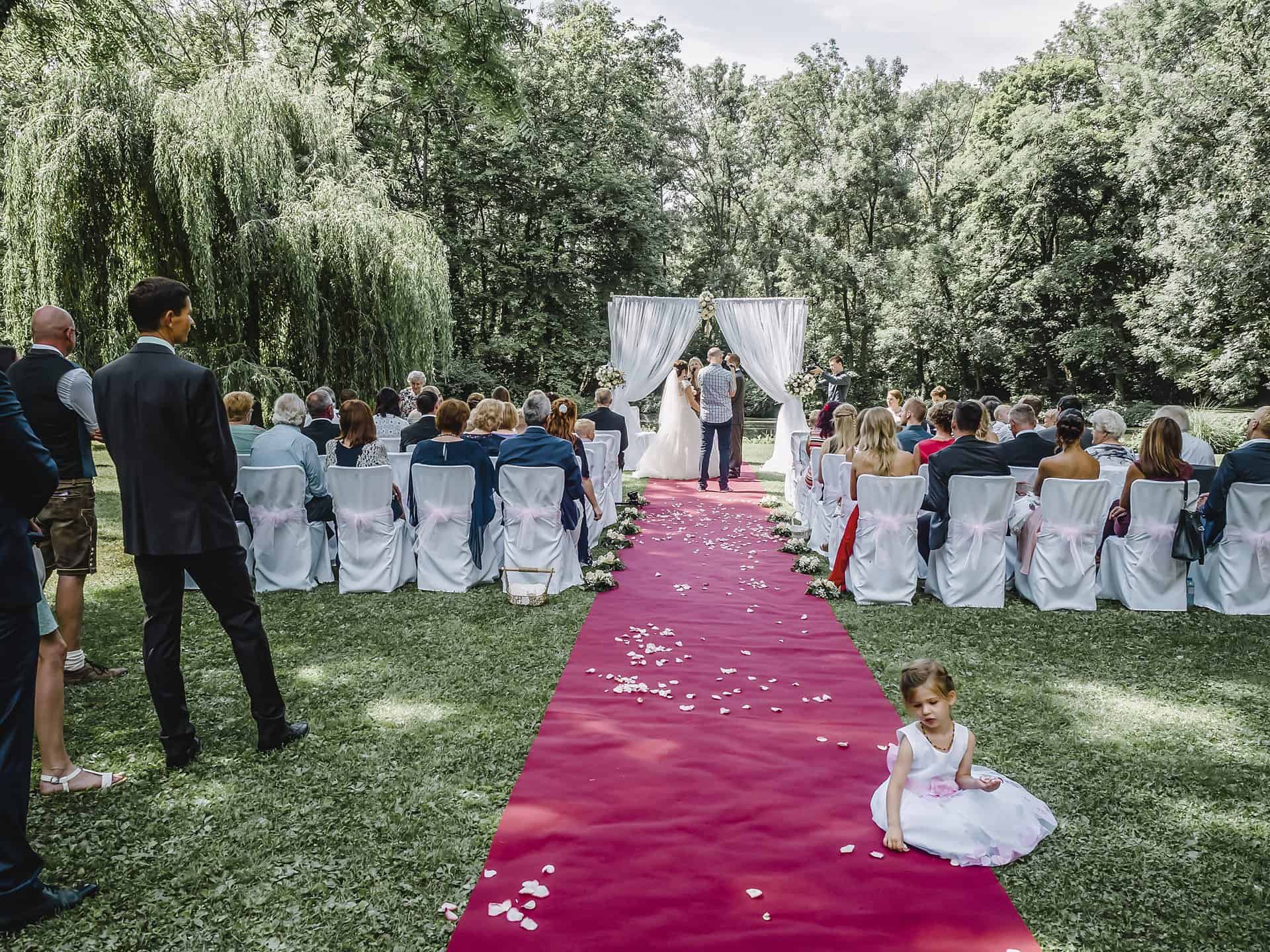 Eine Hochzeitszeremonie mit einem kleinen Mädchen auf dem roten Teppich.