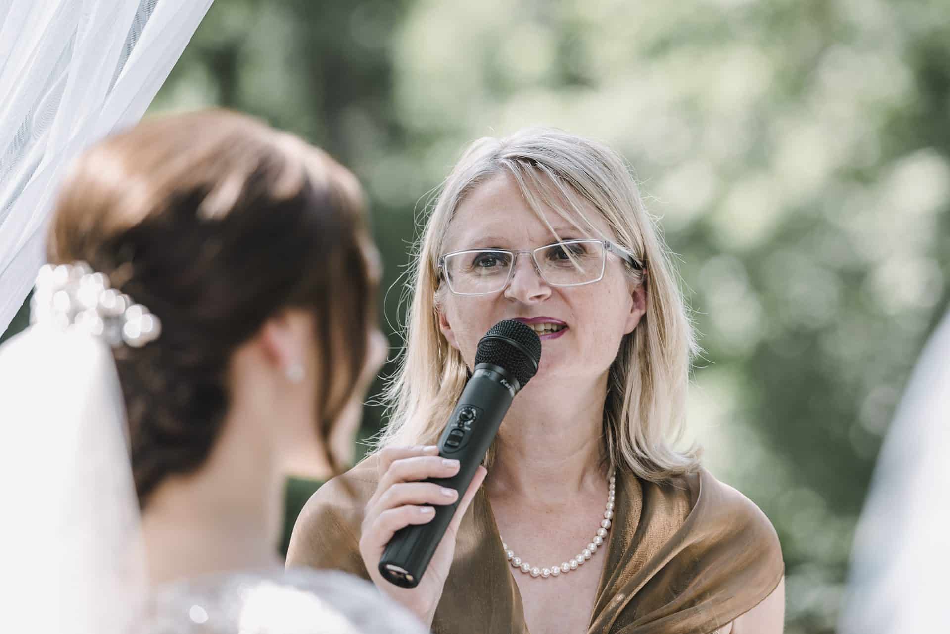 Eine Frau spricht bei einer Hochzeit in ein Mikrofon.