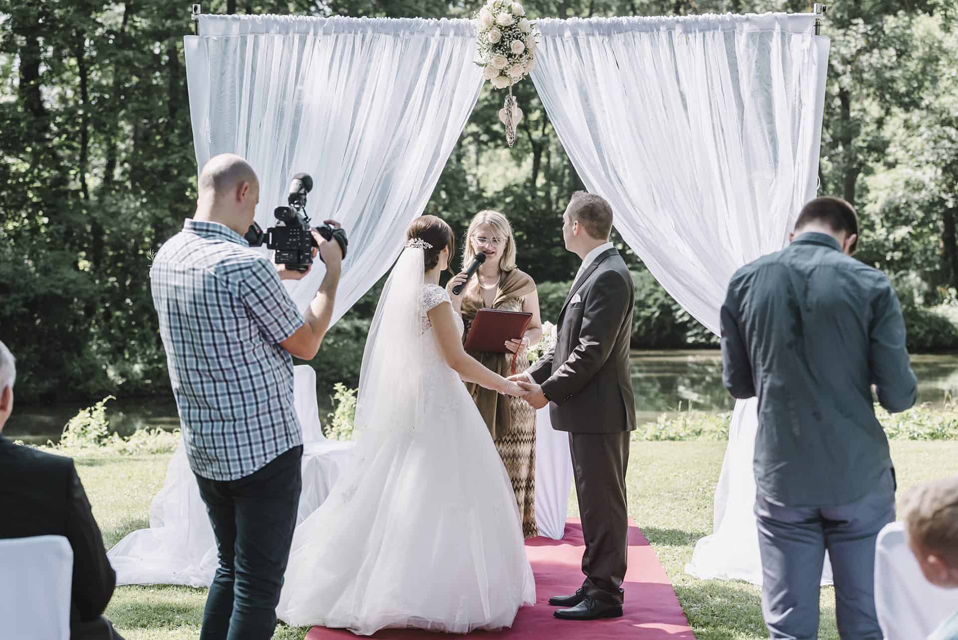 Eine Braut und ein Bräutigam geben sich vor der Kamera das Ja-Wort.