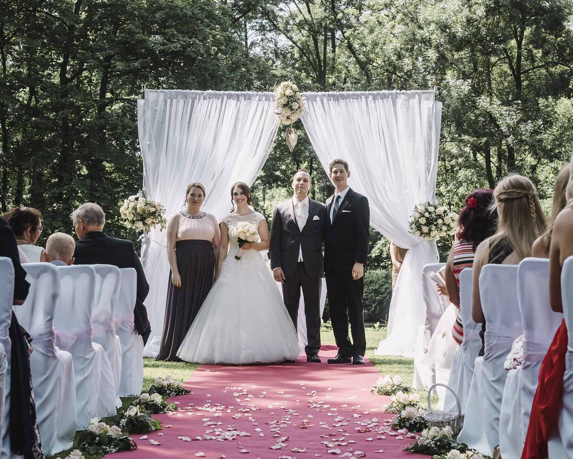Eine Hochzeitszeremonie mit Braut und Bräutigam auf einem roten Teppich.