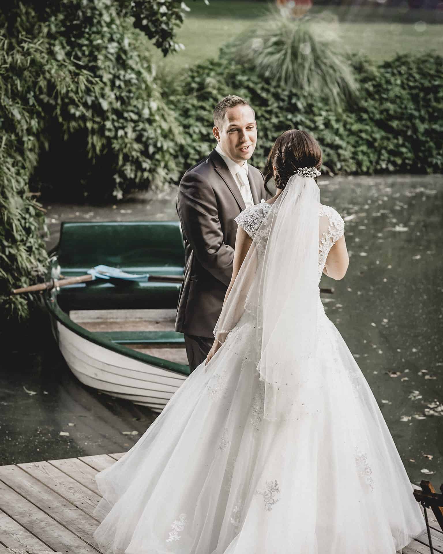 Eine Braut und ein Bräutigam stehen auf einem Steg neben einem Boot.