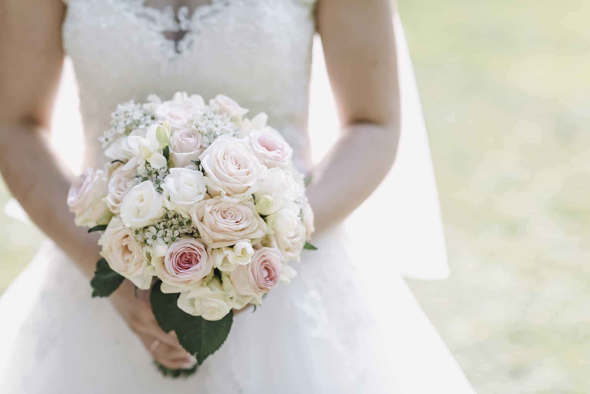 Eine Braut hält einen Strauß rosa und weißer Rosen.