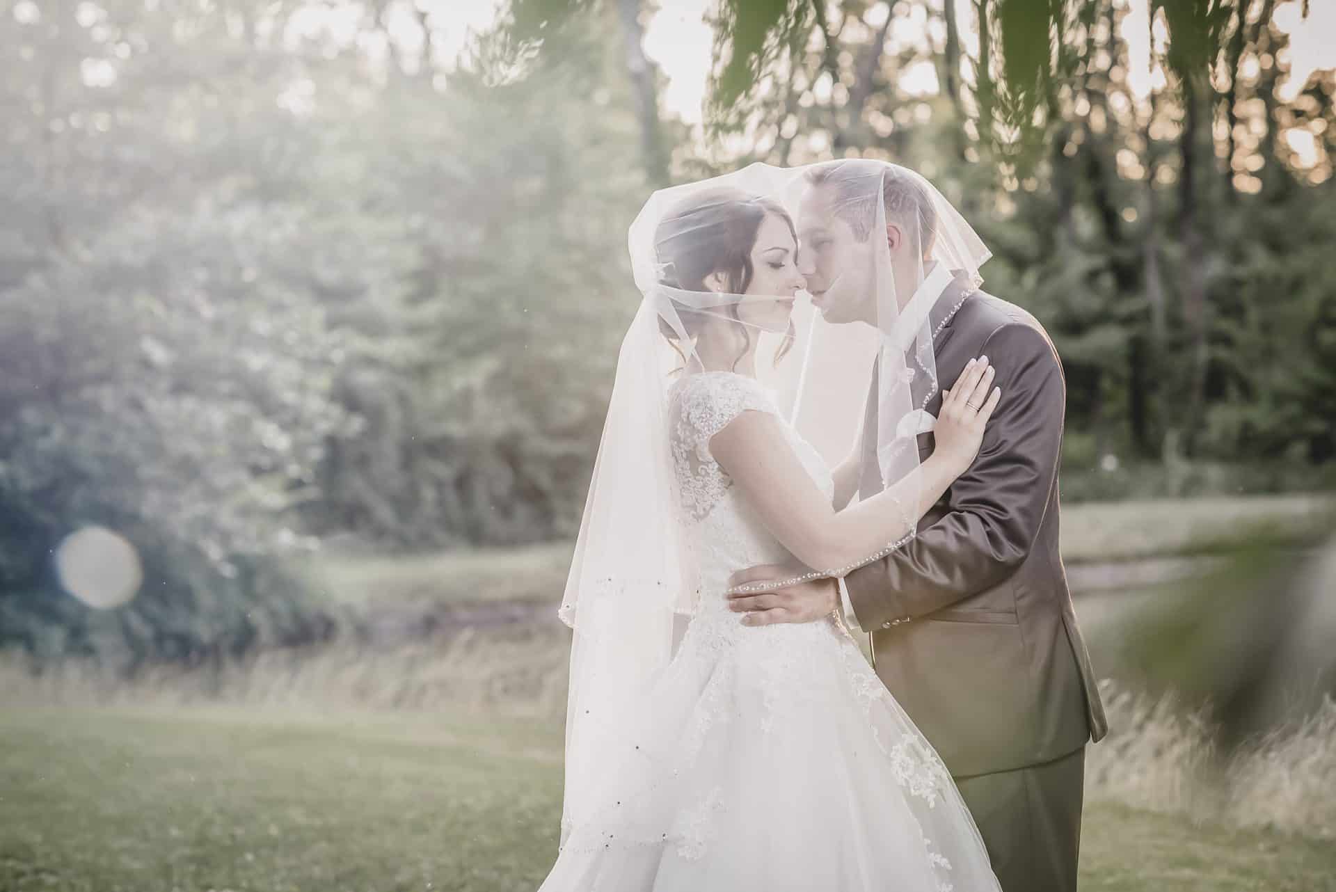 Eine Braut und ein Bräutigam küssen sich auf einem Feld.