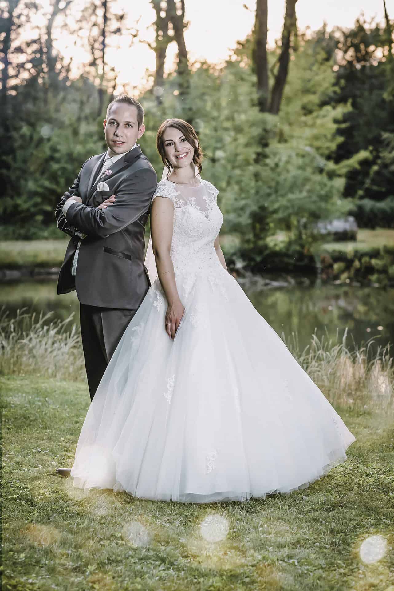 Eine Braut und ein Bräutigam posieren vor einem Teich.