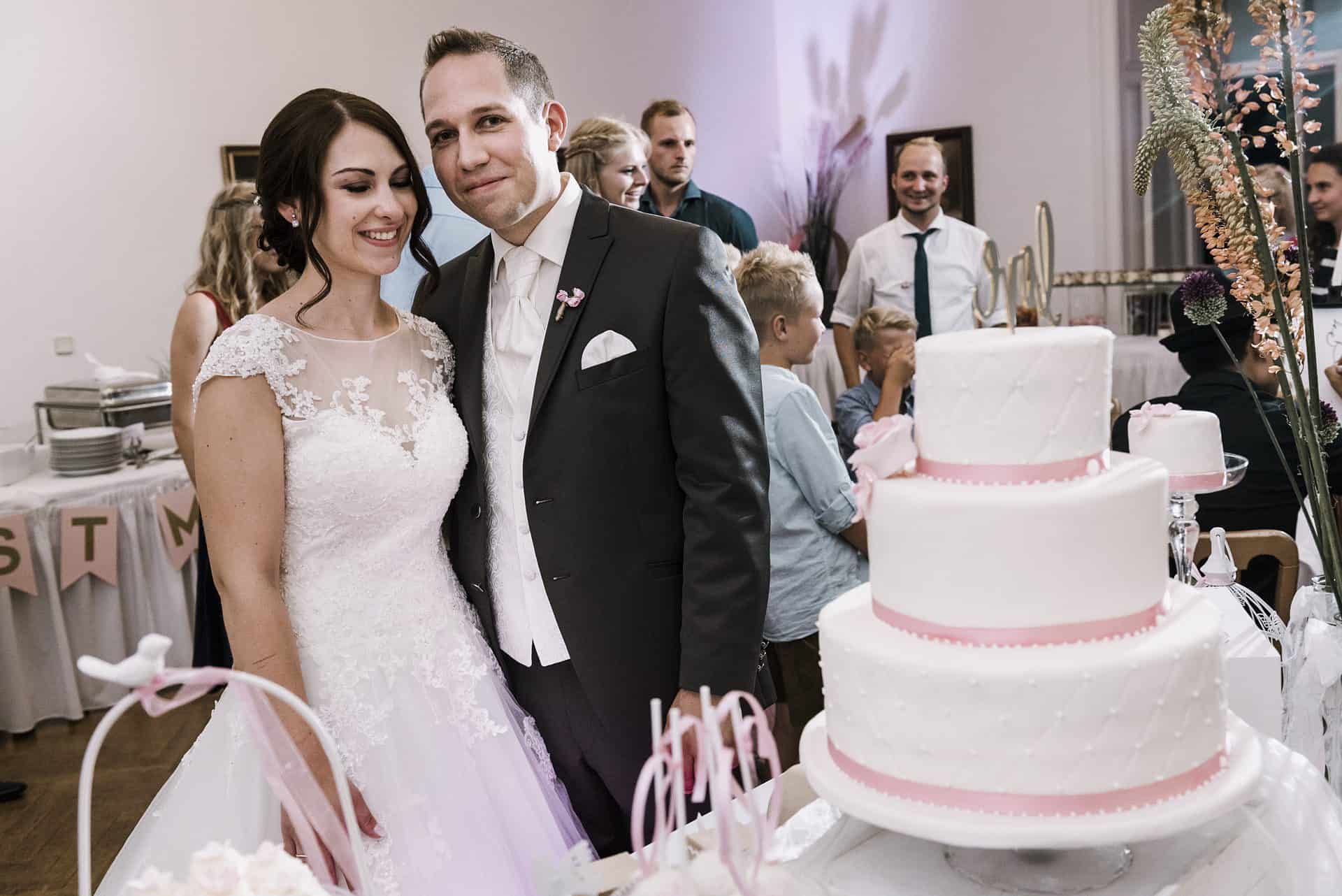 Ein Brautpaar steht vor einer Torte.