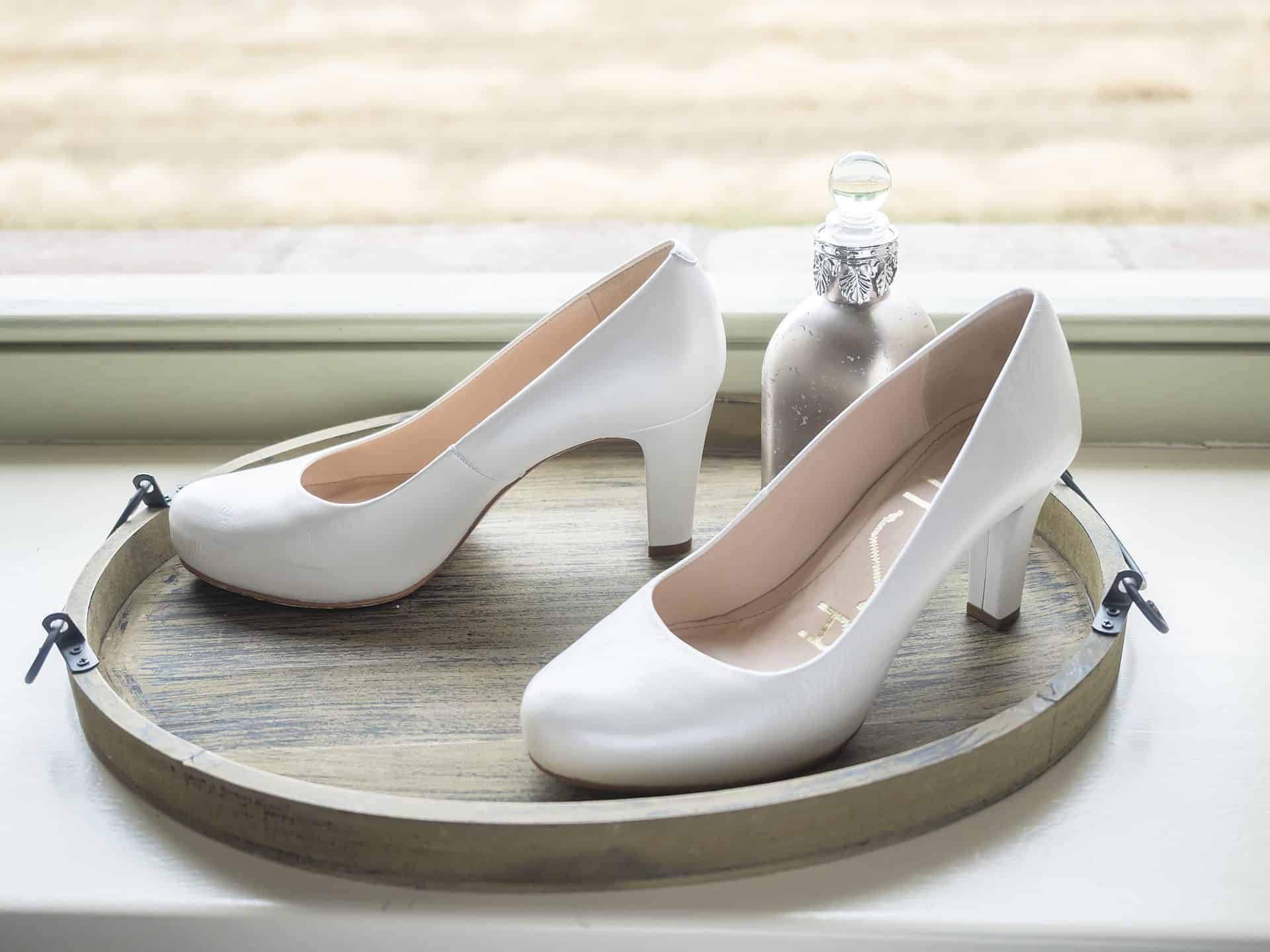 Ein Paar weiße Schuhe mit hohen Absätzen, die auf einem Tablett liegen.