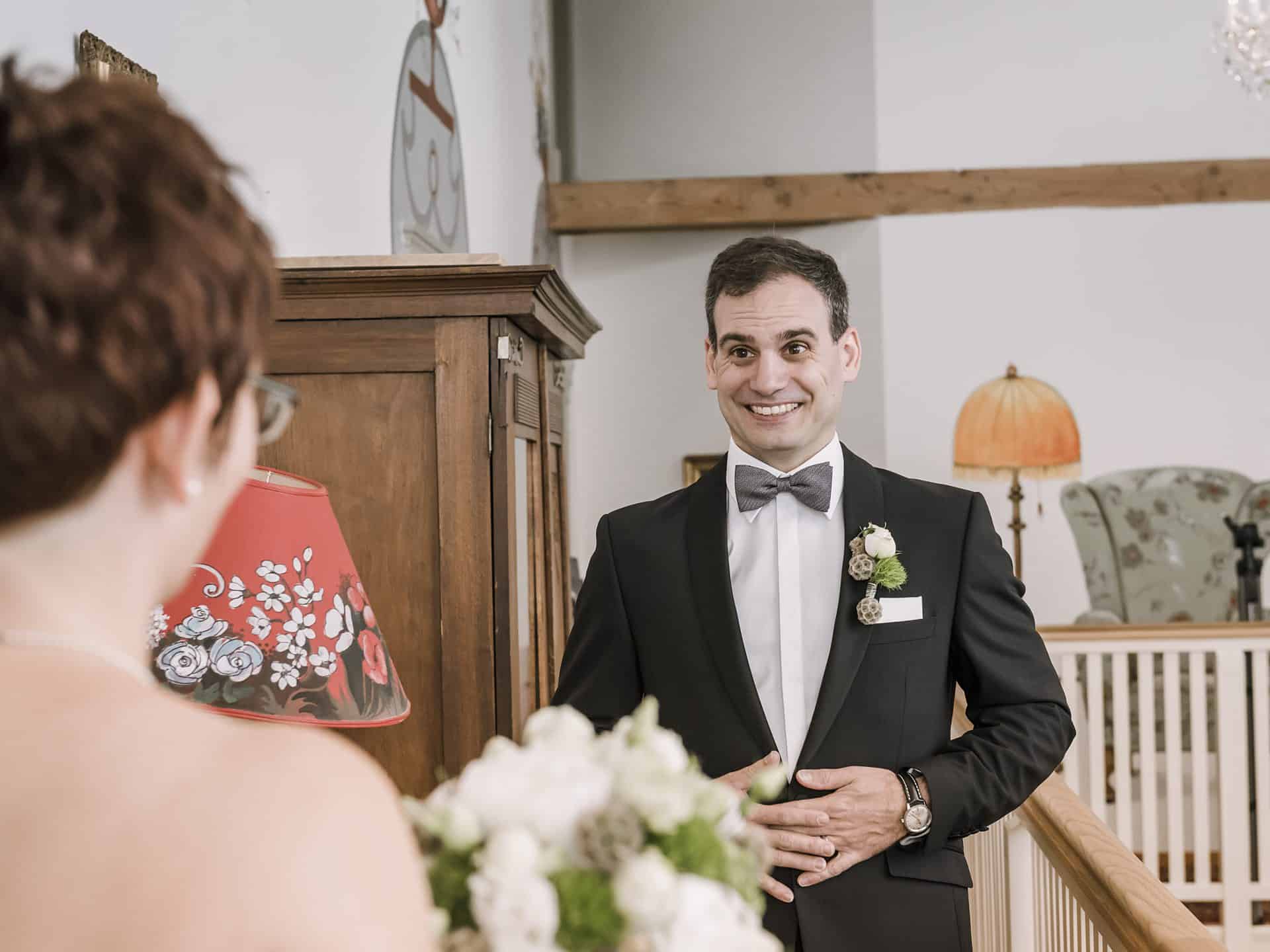 Ein Mann im Smoking lächelt den Bräutigam an.