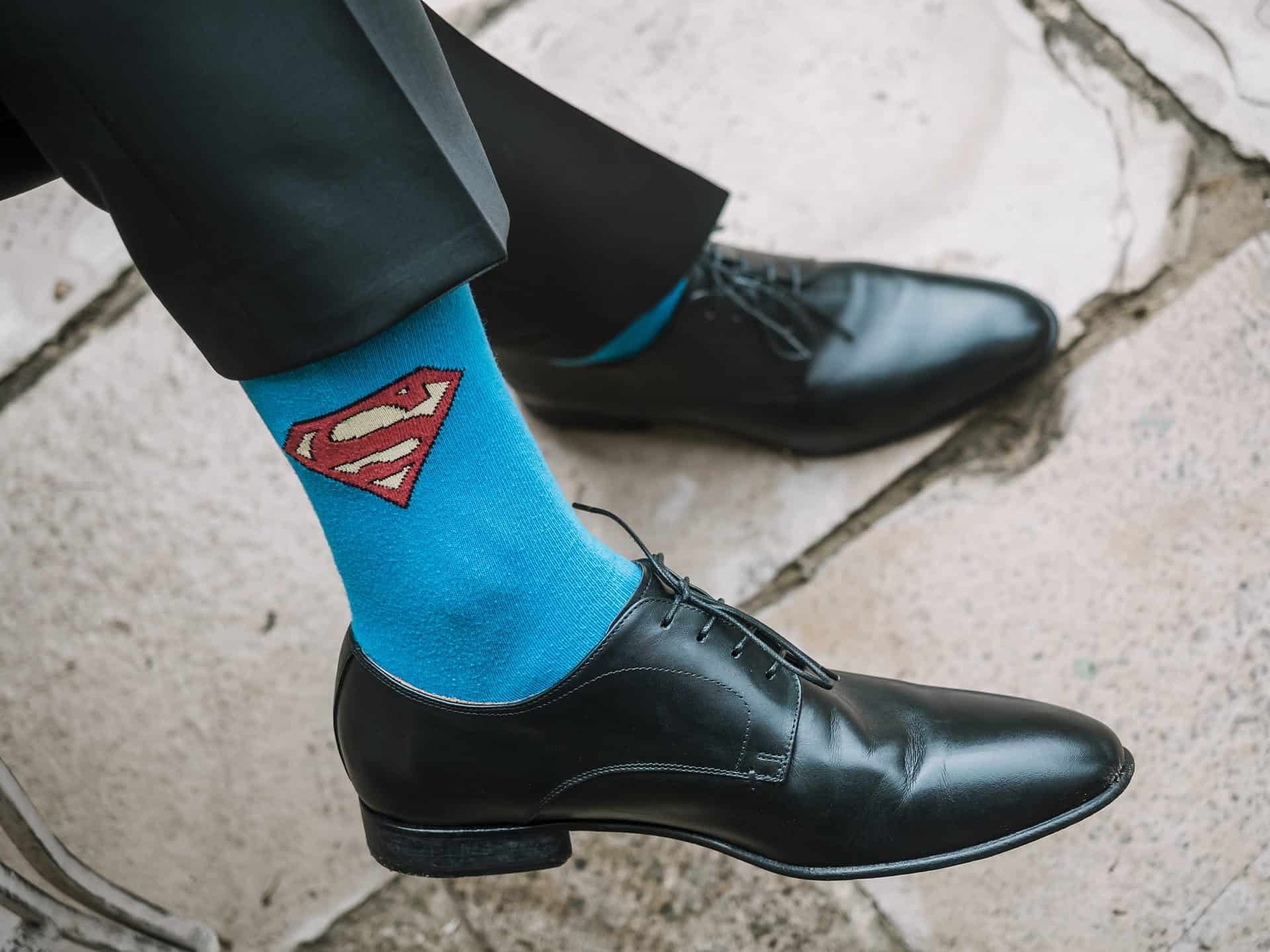Ein Mann, der eine blaue Superman-Socke und schwarze Schuhe trägt.