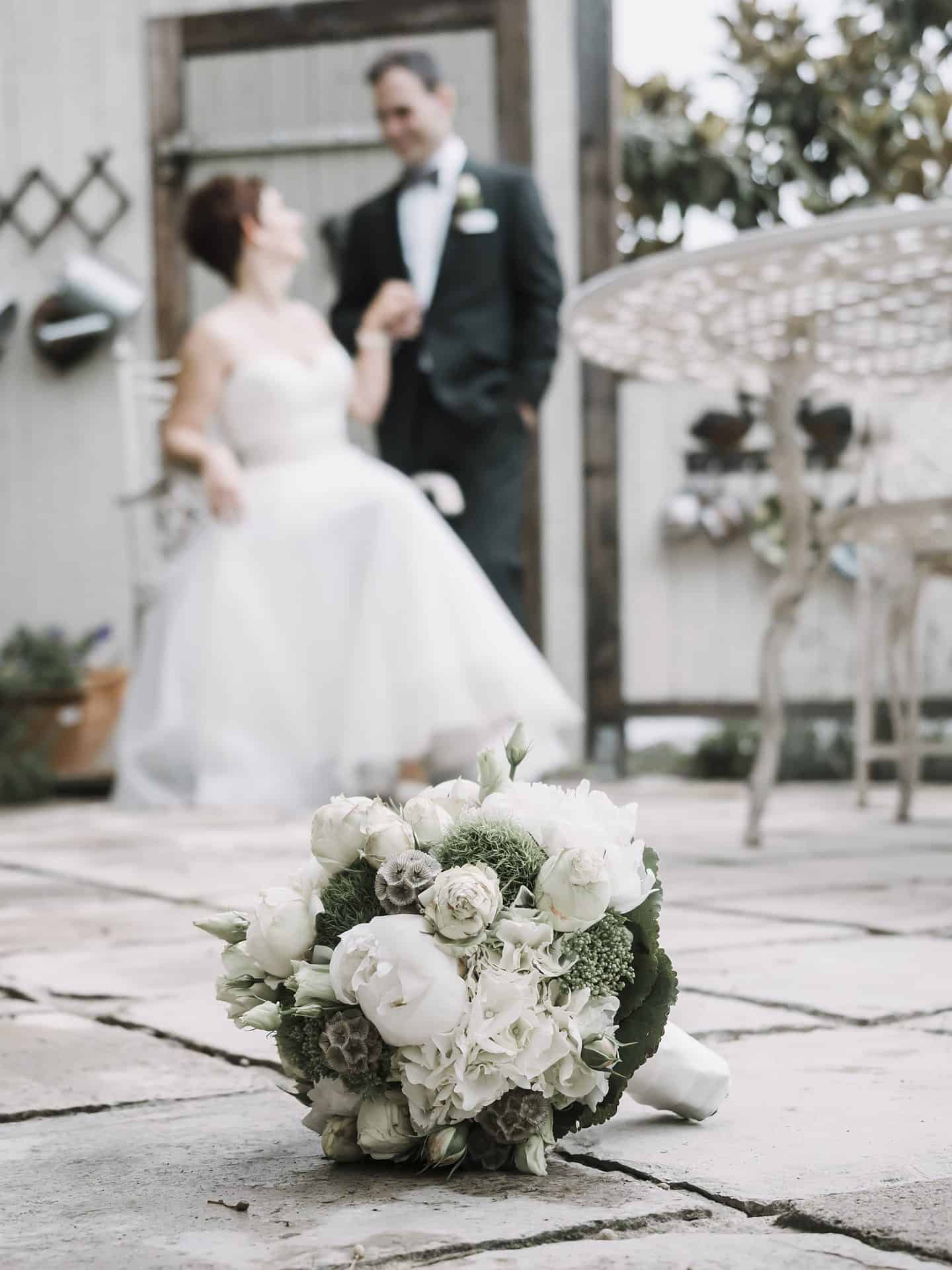 Eine Braut und ein Bräutigam stehen neben einem Blumenstrauß.