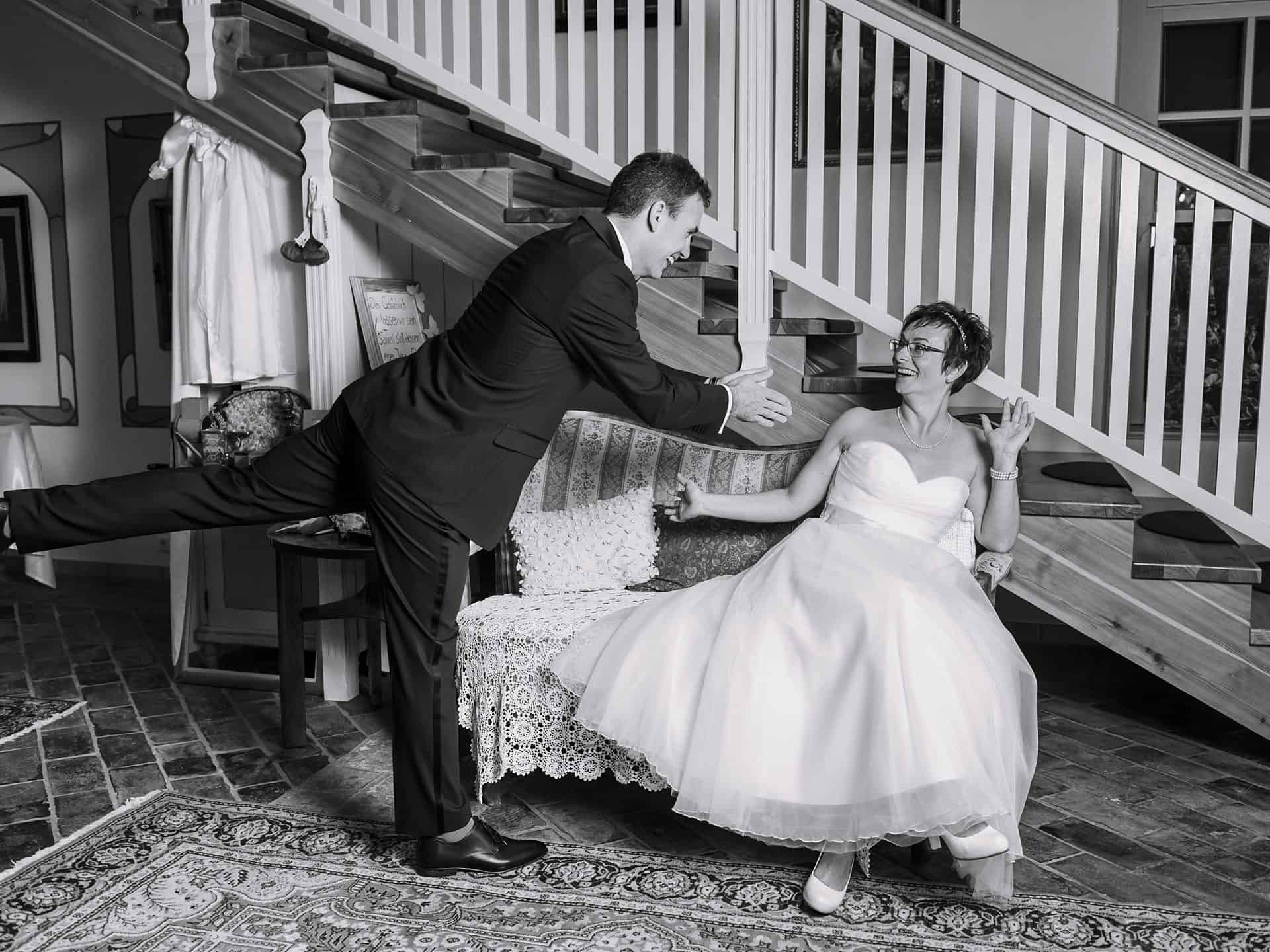 Ein Brautpaar sitzt auf einer Couch vor einer Treppe.