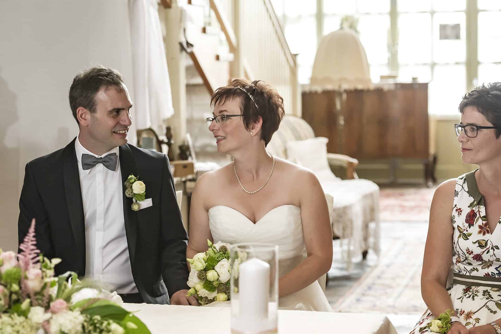 Eine Braut und ein Bräutigam sitzen an einem Tisch mit Blumen.