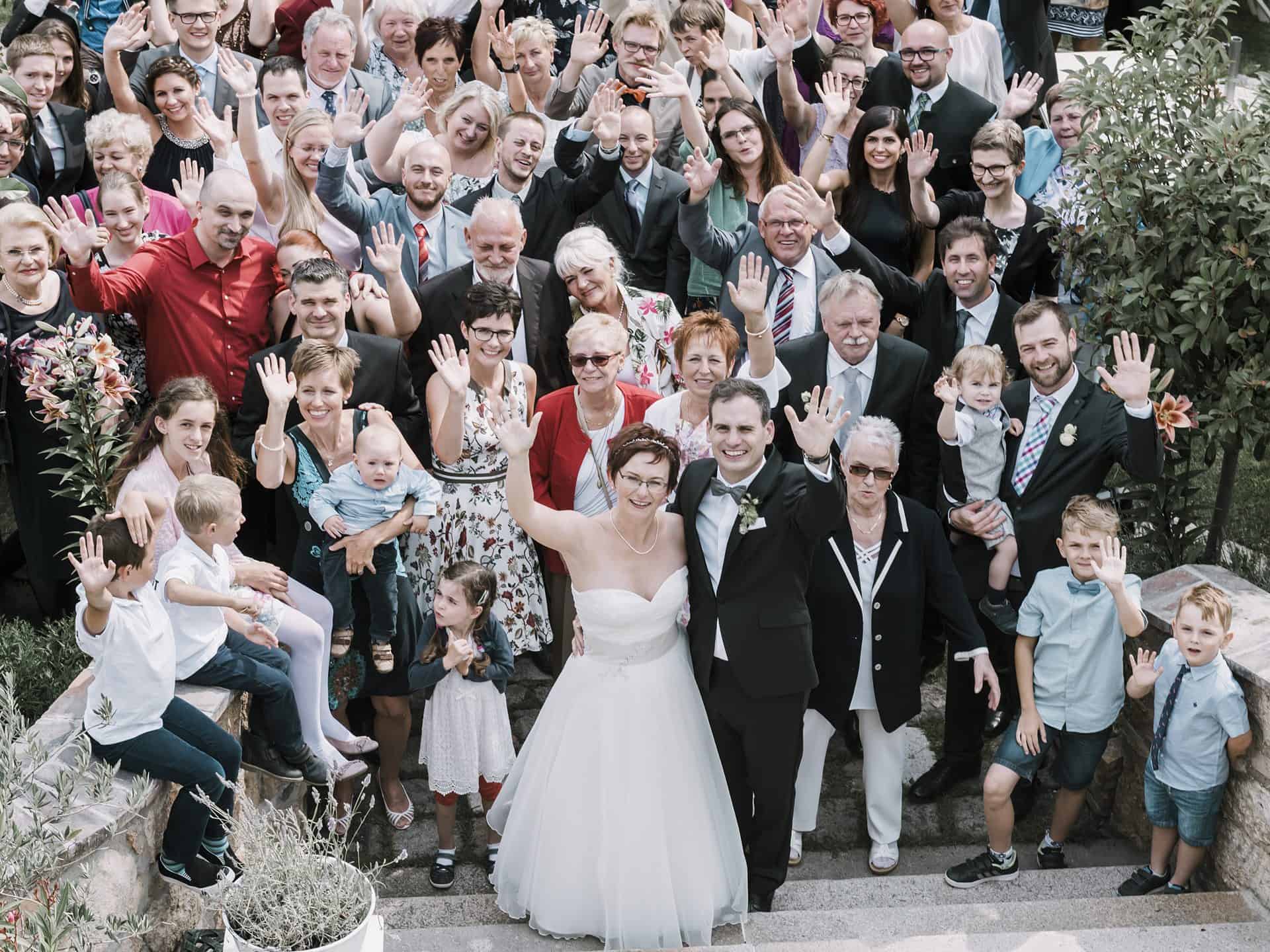 Eine große Gruppe von Menschen posiert für ein Hochzeitsfoto.