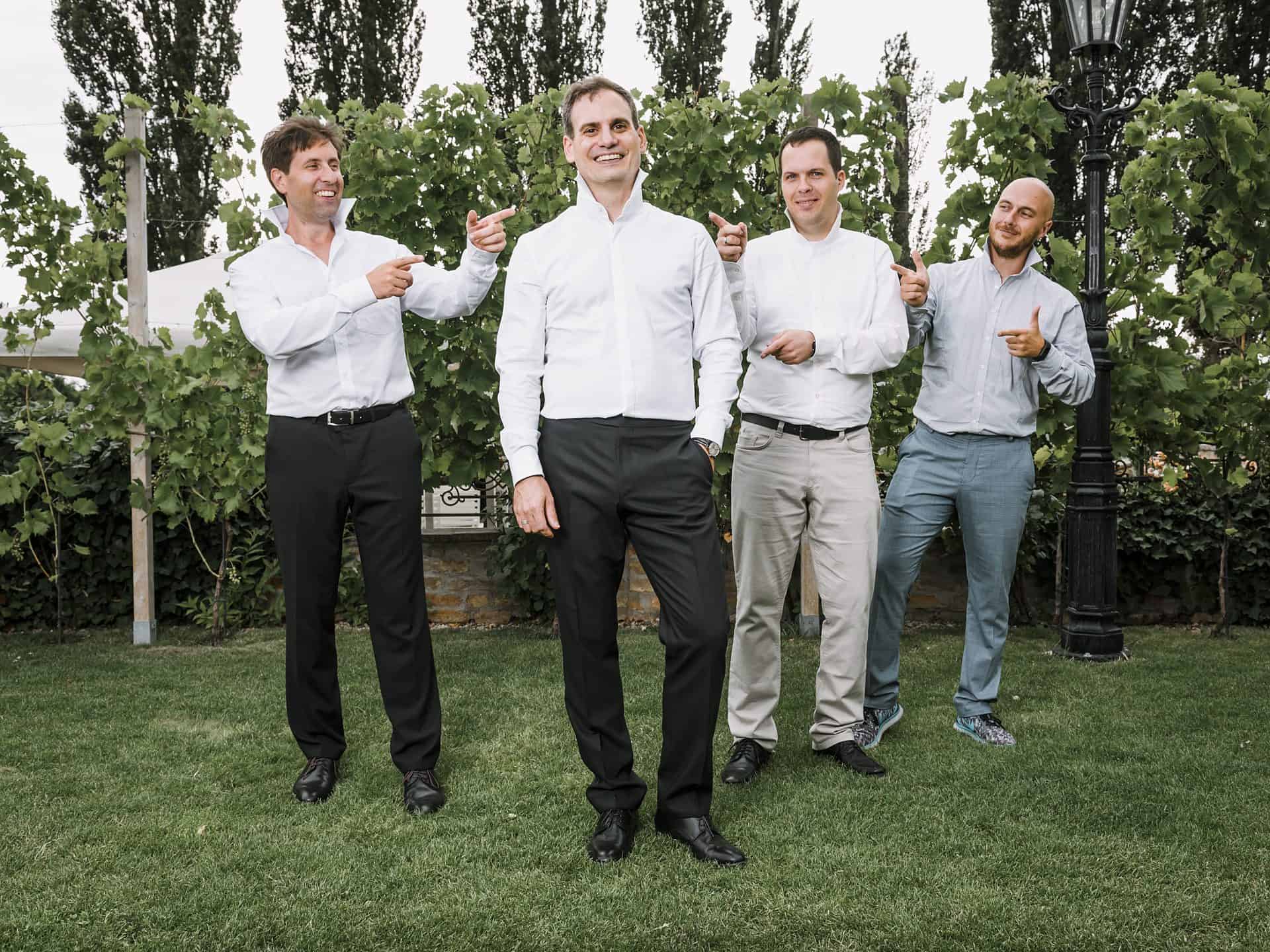Eine Gruppe Männer posiert vor einem Weinberg.