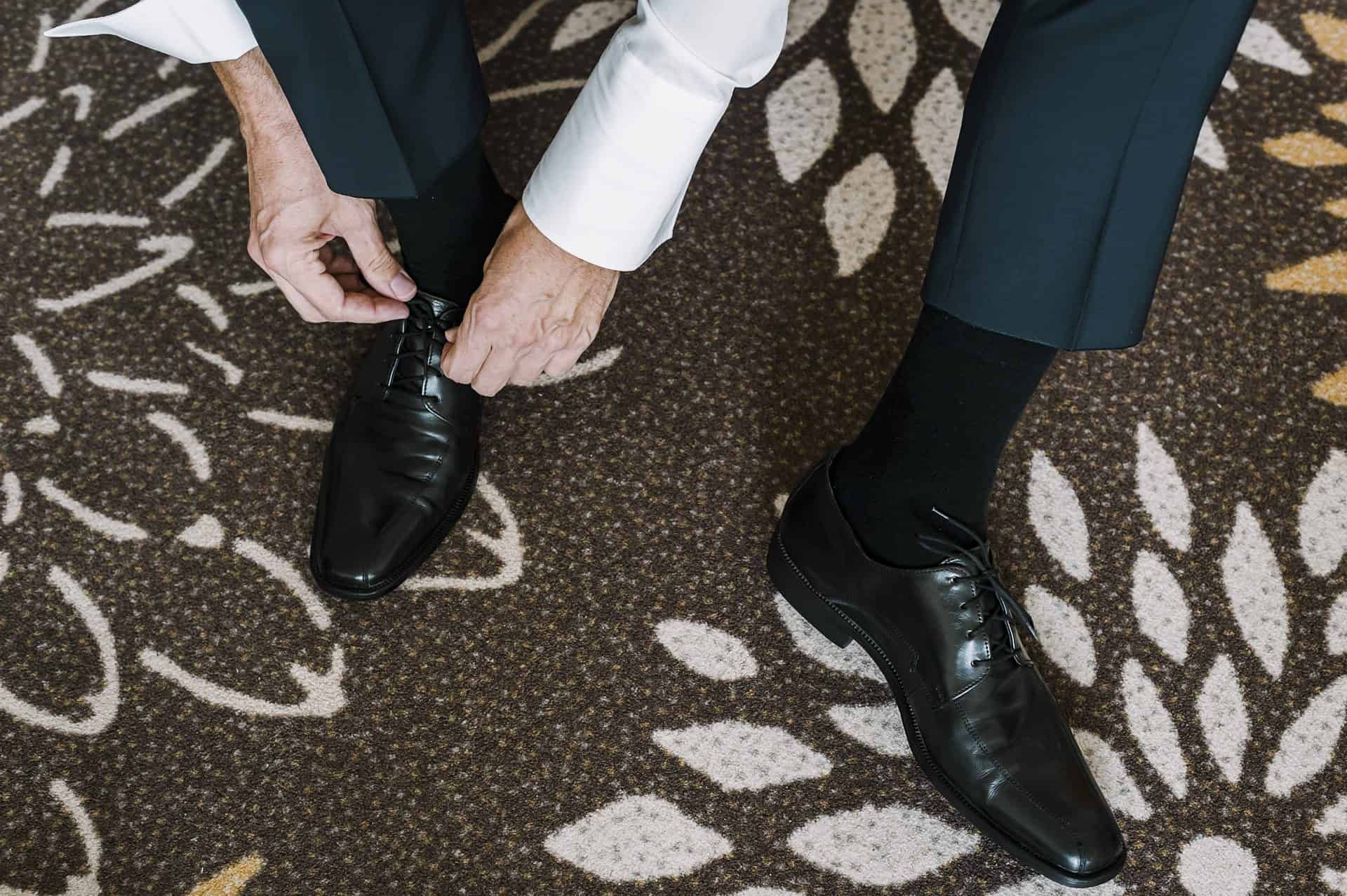 Ein Mann bindet seine Schuhe auf einem Teppich.