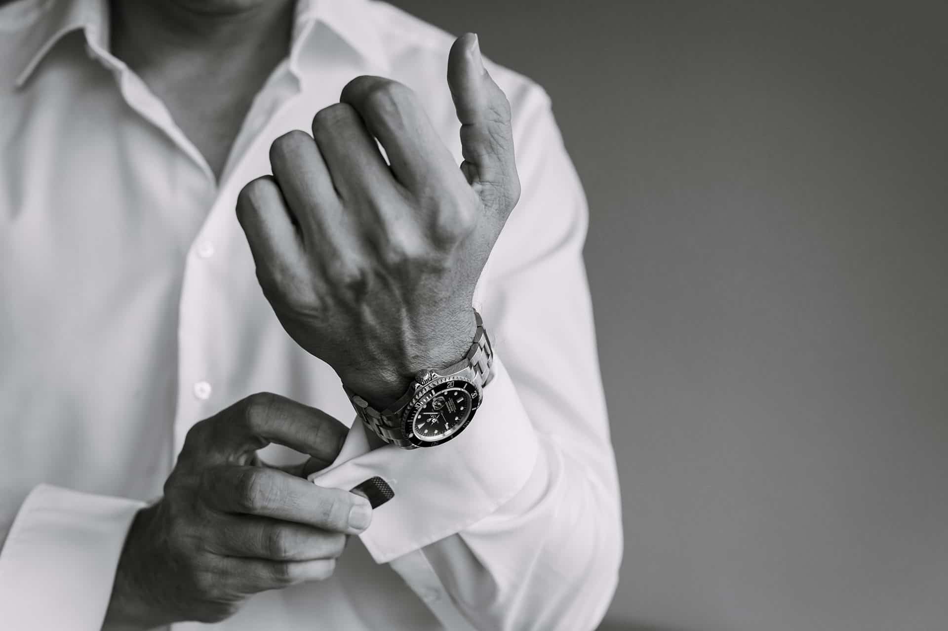 Ein Mann im weißen Hemd stellt seine Uhr ein.