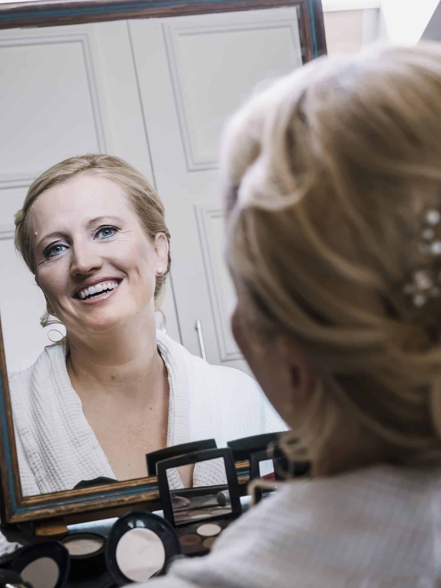 Eine Braut lächelt vor einem Spiegel.